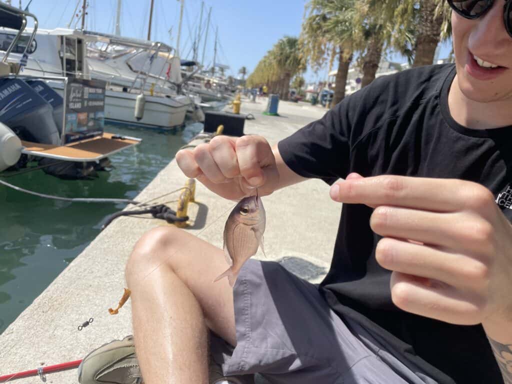 Man holding a small fish that he has just caught