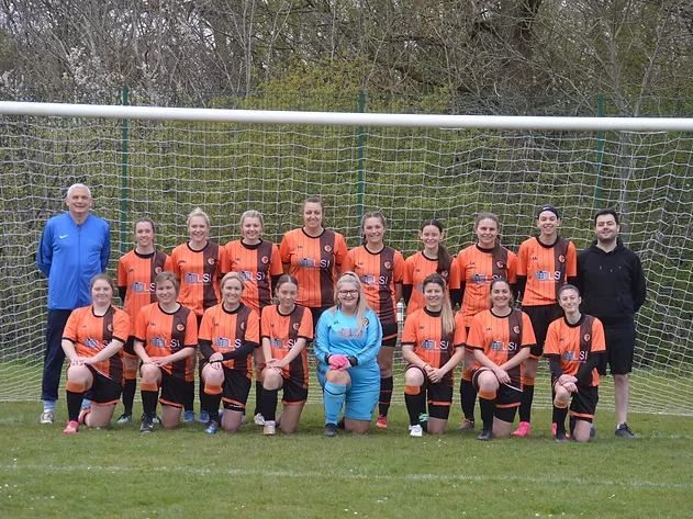 Womens football team having a team photo on the pitch